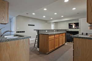 Kitchen with a sink, recessed lighting, a kitchen bar, and light carpet