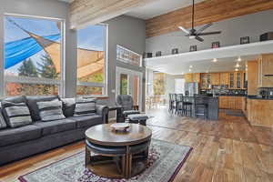 Living area featuring high vaulted ceiling, a ceiling fan, recessed lighting, beam ceiling, and hardwood / wood-style flooring