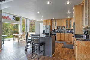 Kitchen with stainless steel fridge with ice dispenser, recessed lighting, black dishwasher, a kitchen island, and decorative backsplash