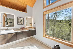 Bathroom featuring high vaulted ceiling, a sink, double vanity, wooden ceiling, and tile patterned flooring