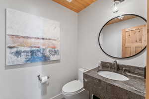 Bathroom with toilet, wood ceiling, and a sink