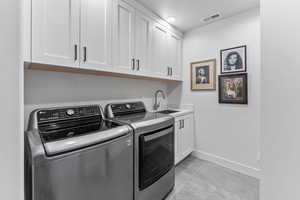 Laundry area with a sink, washer and dryer, cabinet space, baseboards, and visible vents