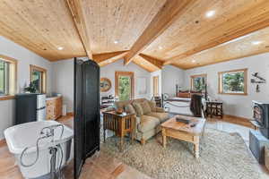 Living room featuring recessed lighting, a wood stove, vaulted ceiling with beams, and wooden ceiling