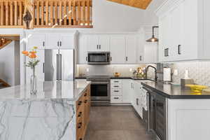Kitchen with high vaulted ceiling, a sink, white cabinets, appliances with stainless steel finishes, and wine cooler