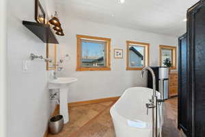 Full bathroom with baseboards, a freestanding tub, a sink, and recessed lighting