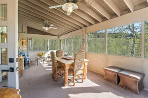 Sunroom / solarium featuring beamed ceiling and ceiling fan