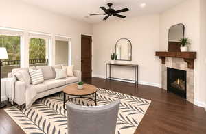 Living room with wood finished floors, ceiling fan, a tiled fireplace, baseboards, and recessed lighting