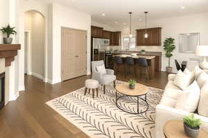 Living area with arched walkways, dark wood-style flooring, baseboards, recessed lighting, and a fireplace