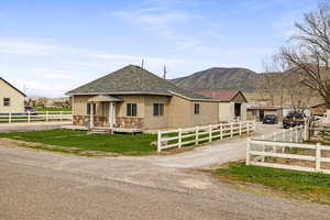 View of front of home featuring a front lawn, driveway, fence private yard, roof with shingles, and a mountain view