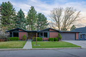 View of front of property with an attached garage, concrete driveway, and a front yard