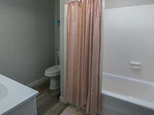 Bathroom featuring visible vents, toilet, shower / bath combo with shower curtain, wood finished floors, and a skylight