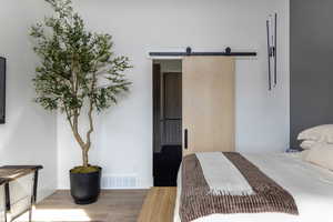 Priamry Bedroom featuring baseboards, wood finished floors, visible vents, and a barn door