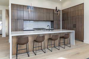 Kitchen featuring decorative backsplash, modern cabinets, a sink, and light wood-style floors