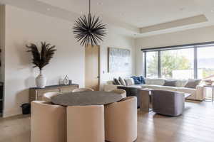 Living area with recessed lighting, light wood-style flooring, and a tray ceiling