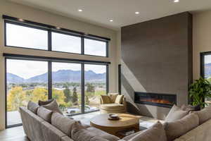 Living area featuring a tile fireplace, light wood-style flooring, a high ceiling, a mountain view, and recessed lighting