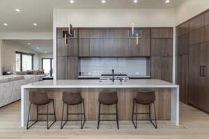 Kitchen featuring light countertops, dark brown cabinets, a sink, modern cabinets, and a spacious island