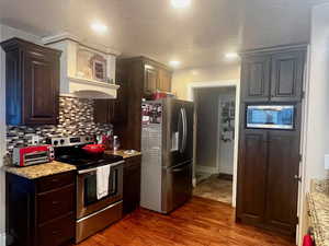 Kitchen featuring tasteful backsplash, dark brown cabinetry, wood finished floors, and stainless steel appliances