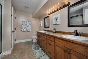Bathroom featuring double vanity and a shower with door