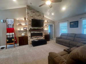 Living area featuring baseboards, ceiling fan, a fireplace, vaulted ceiling, and carpet flooring
