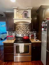 Kitchen featuring custom range hood, dark brown cabinets, and stainless steel appliances