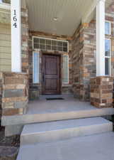 Entrance to property featuring a porch and stone siding