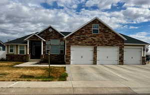 Craftsman-style home featuring an attached garage, driveway, and stone siding