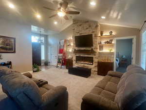 Living room with a stone fireplace, ceiling fan, carpet, recessed lighting, and lofted ceiling
