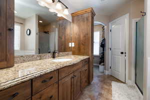 Bathroom featuring stone tile flooring, vanity, and a shower with door