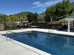 Community pool with a mountain view and fence