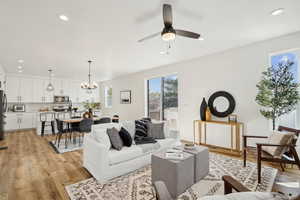 Living area featuring recessed lighting, light wood-type flooring, and ceiling fan with notable chandelier