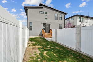 Rear view of property featuring stucco siding and fence
