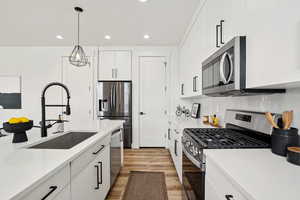 Kitchen featuring light wood-type flooring, a sink, recessed lighting, and appliances with stainless steel finishes