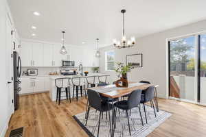 Dining area featuring recessed lighting, visible vents, light wood-type flooring, baseboards, and a notable chandelier