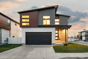 Contemporary house with a gate, fence, a front lawn, stucco siding, and a garage