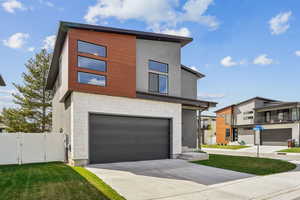Contemporary house featuring a gate, fence, concrete driveway, stone siding, and a garage