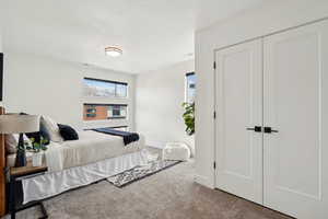 Carpeted bedroom with a closet, visible vents, a textured ceiling, and multiple windows