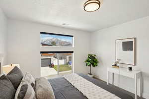 Bedroom with baseboards, a textured ceiling, visible vents, and access to exterior