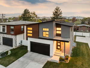 Contemporary home with an attached garage, a lawn, fence, and a mountain view