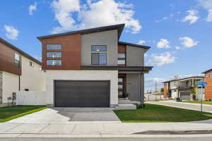 Modern home with a gate, driveway, an attached garage, a front yard, and stucco siding