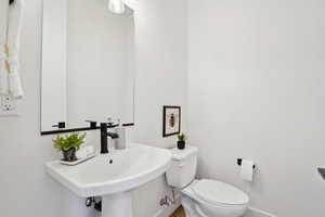Half bathroom featuring baseboards, a sink, and toilet