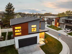 Contemporary home featuring an attached garage, fence, a yard, and concrete driveway