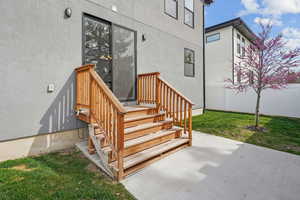 Entrance to property featuring stucco siding, a patio, and a lawn