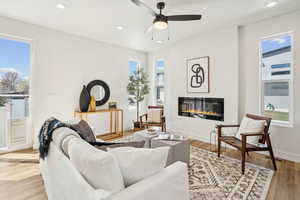 Living area with visible vents, plenty of natural light, a glass covered fireplace, and ceiling fan