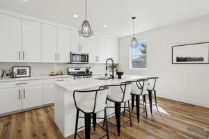 Kitchen with a kitchen breakfast bar, stainless steel appliances, light countertops, a sink, and tasteful backsplash