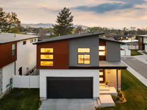 Contemporary house with a mountain view, driveway, fence, a garage, and a front yard