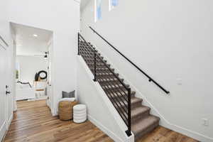 Staircase featuring recessed lighting, wood finished floors, baseboards, and plenty of natural light