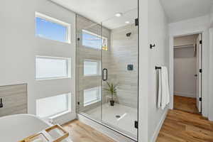 Full bathroom with a spacious closet, a healthy amount of sunlight, a soaking tub, and a stall shower