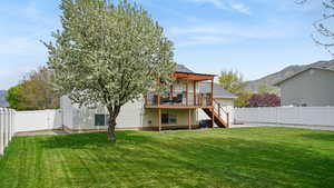 Back of property featuring a deck with mountain view, a lawn, a fenced backyard, and staircase