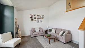 Carpeted living room with vaulted ceiling and bay window