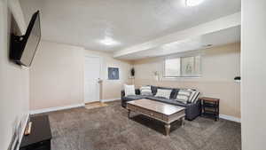 Living area with visible vents, carpet, baseboards, and a textured ceiling